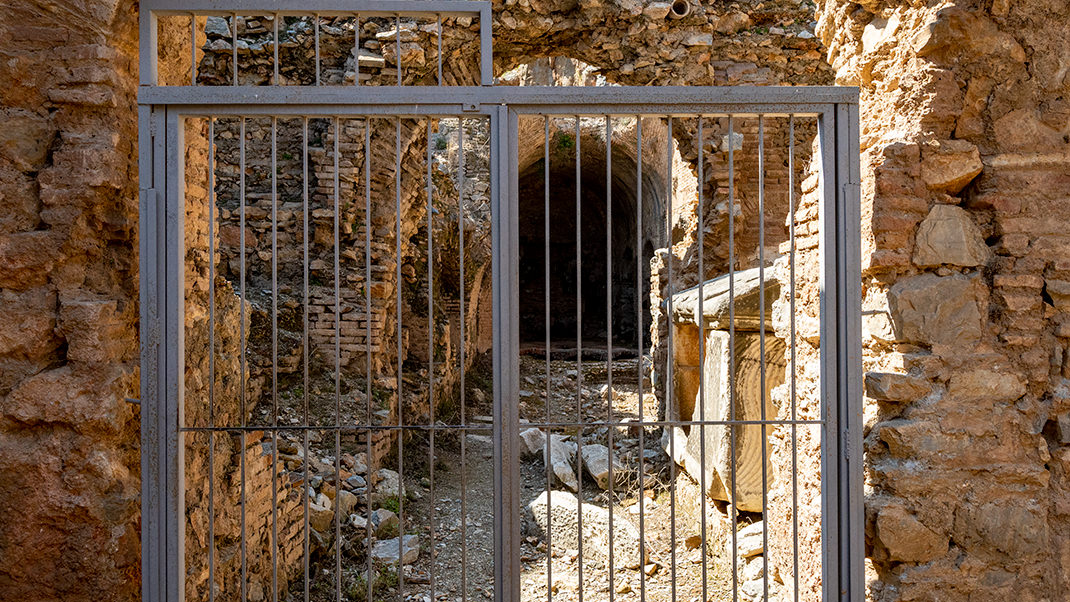 Behind the bars, a burial chamber is visible